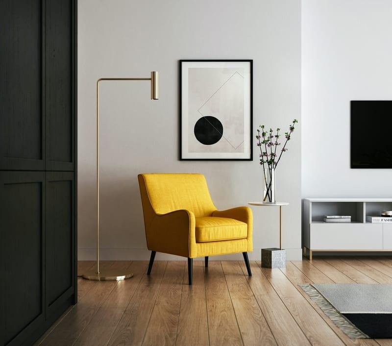 Mustard armchair beside a brass floor lamp